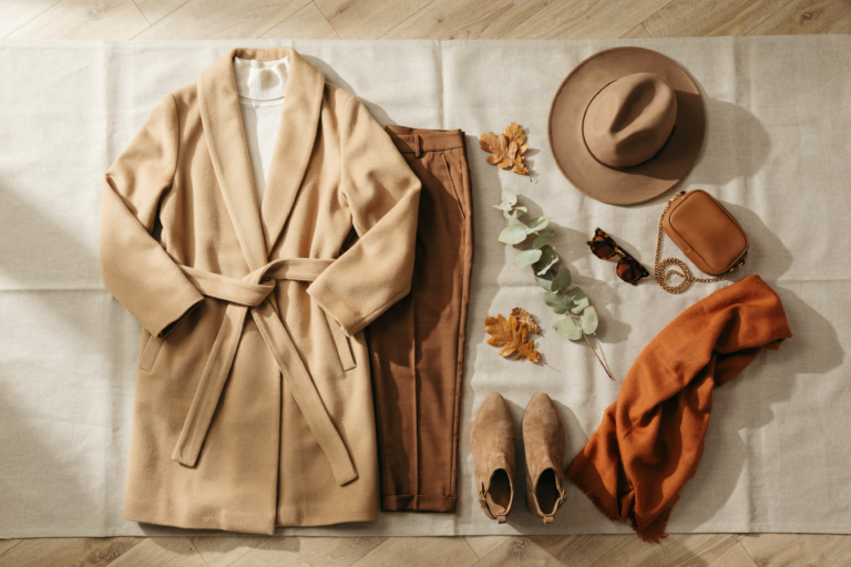 an editoral flat lay of a fall outfit include shoes , hat , wrap coat, trousers